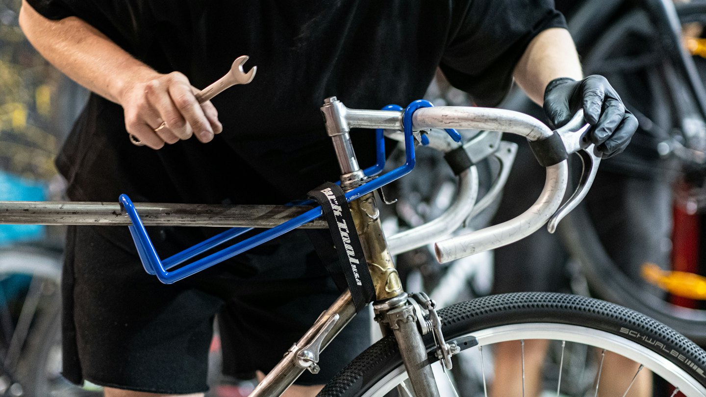 Cyklist mekar med cykelstyre med en skiftnyckel.