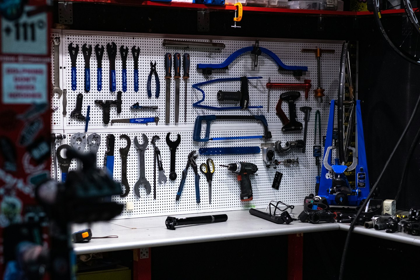 Pegboardvägg med organiserade cykelreparationsverktyg och arbetsbänk.